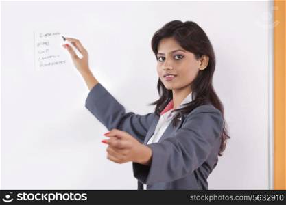 Portrait of female executive writing on white board