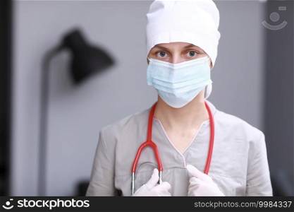 Portrait of female family doctor wearing in medical mask, gloves and form. Stethoscope on the neck. Isolated on gray background. Healthcare And Medicine. visit home. Disease prevention concept. Portrait of female family doctor wearing in medical mask, gloves and form. Stethoscope on the neck. Isolated on gray background. Healthcare And Medicine. visit home. Disease prevention concept.