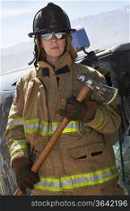 Portrait of female firefighter holding axe