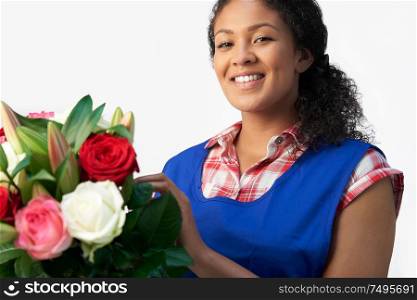 Portrait Of Female Florist Arranging Bouquet Of Lillies And Roses Against White Background