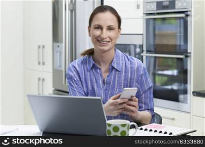 Portrait Of Female Freelance Worker Using Laptop In Kitchen At Home
