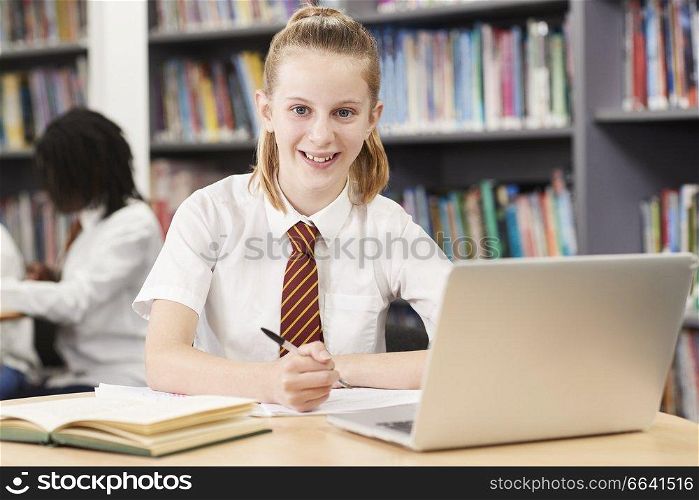Portrait Of Female High School Student Wearing Uniform Working At Laptop In Library