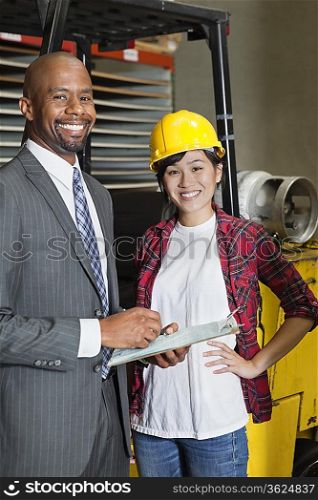 Portrait of female industrial worker standing with male inspector