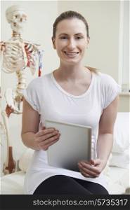 Portrait Of Female Osteopath In Consulting Room With Digital Tablet