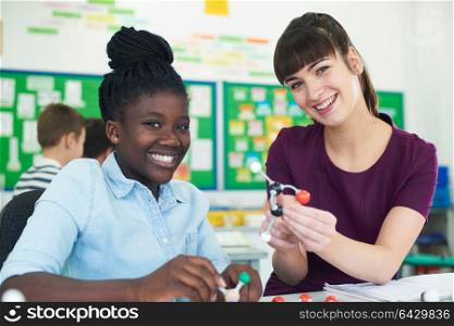 Portrait Of Female Pupil And Teacher Using Molecular Model Kit In Science Lesson