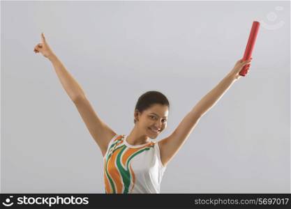 Portrait of female relay runner celebrating victory isolated over gray background