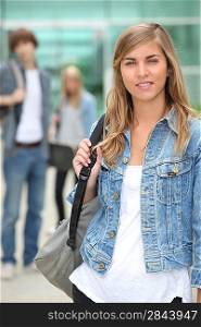 Portrait of female student in denim jacket with friends in the background
