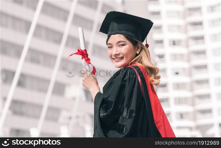 Portrait of female student wearing uniform and cap of graduation. She holding certificate and smiling with success, happiness, proud. Education Concept.