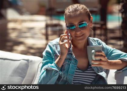 Portrait of Female Student with Cellphone and Cup of Coffee in the City. Enjoying Coffee Break in Outdoors Cafe. Modern Life of Young People.
