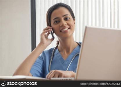 Portrait of female surgeon using mobile phone at desk