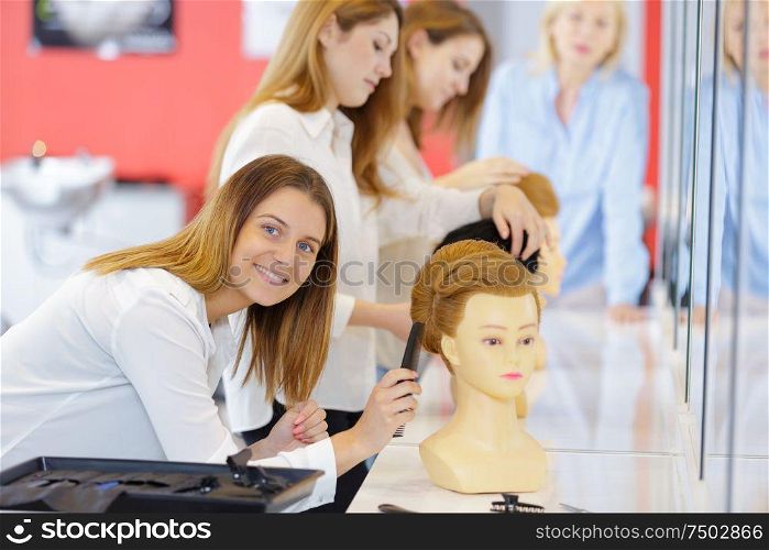 portrait of female trainee haidresser with mannnequin head