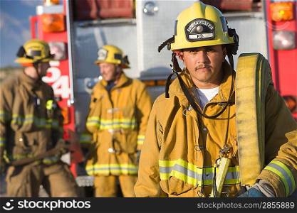 Portrait of firefighter carrying hose