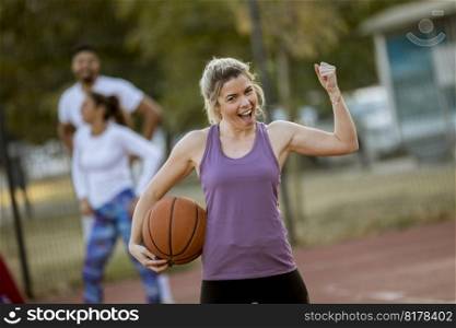 Portrait of fitness young woman with basketball ball playing game outdoor