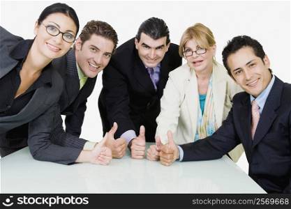 Portrait of five business executives showing thumbs up sign in a meeting