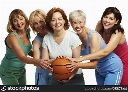Portrait of five mature women holding a basketball and smiling