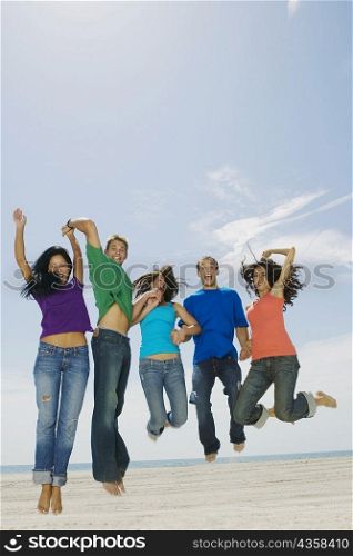 Portrait of five young people jumping on the beach