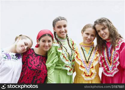Portrait of five young women standing with their arms around each other and smiling