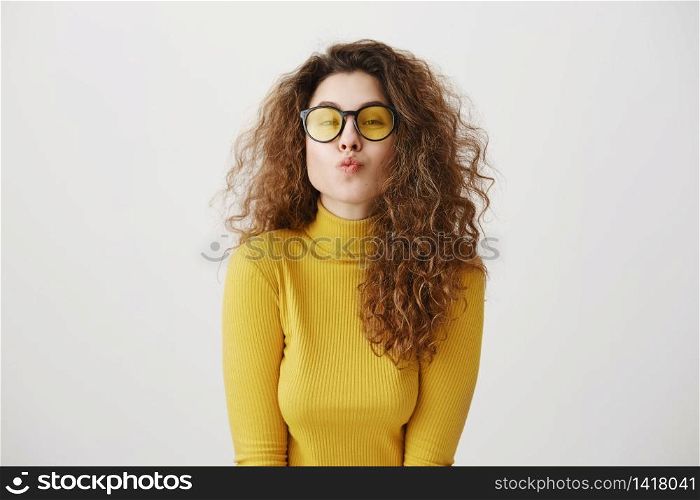Portrait of flirting woman wearing giving air kiss at camera isolated over grey background in studio.. Portrait of flirting woman wearing giving air kiss at camera isolated over grey background in studio