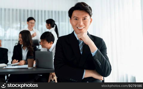 Portrait of focus young successful confident male manager, executive wearing business wear in harmony office arm crossed with blurred meeting background of colleagues, office worker.. Portrait of focus successful confident male manager in harmony office.