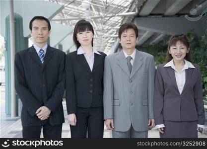 Portrait of four business executives standing side by side