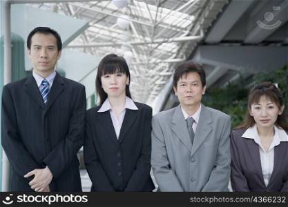 Portrait of four business executives standing side by side