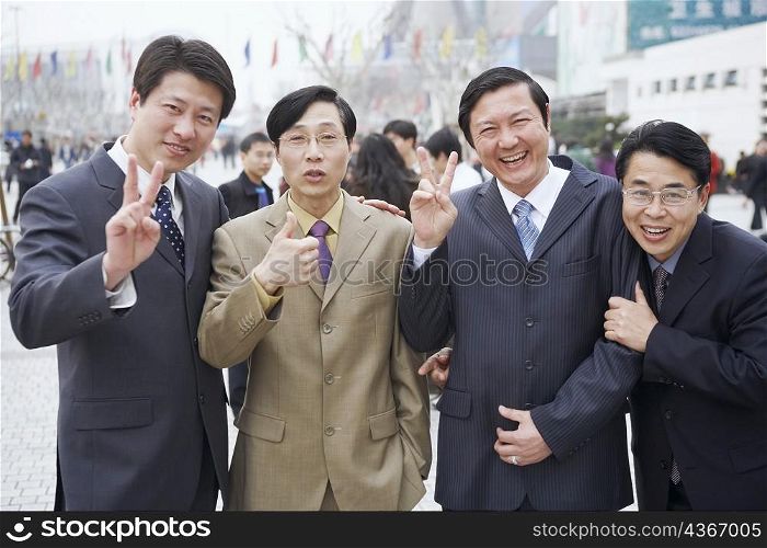 Portrait of four businessmen making hand signs