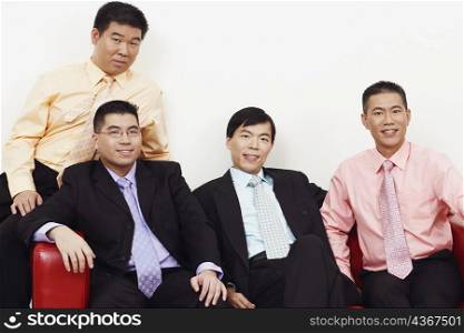 Portrait of four businessmen sitting together on a couch and smiling