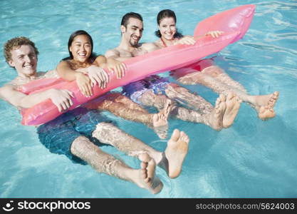 Portrait of four friends in the pool with an inflatable raft