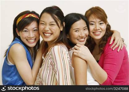 Portrait of four young women hugging each other and posing