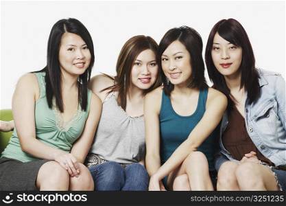 Portrait of four young women sitting on a couch smiling