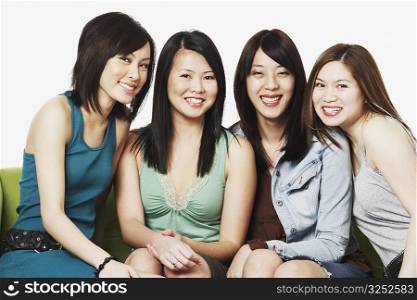 Portrait of four young women sitting on a couch smiling