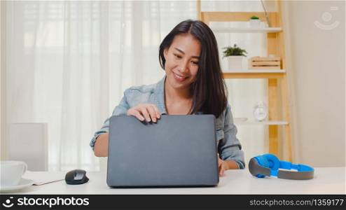 Portrait of freelance smart business women casual wear using laptop working in workplace in living room at home. Happy young Asian girl relax sitting on desk search and do job in internet.