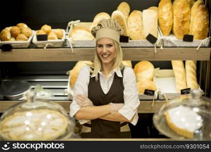 Portrait of friendly female baker with fresh bread smiling in bakery
