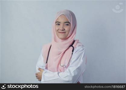 Portrait of friendly, smiling confident Muslim woman doctor in hijab dress holding a stethoscope and looking at camera on white background