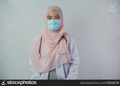 Portrait of friendly, smiling confident Muslim woman doctor in hijab dress wear mask holding a stethoscope and looking at camera on white background