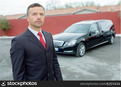 Portrait of funeral director in front of hearse