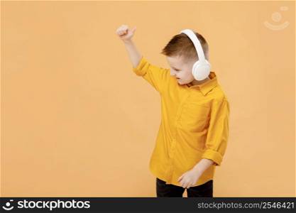 portrait of funny clever school boy with headphones in yellow shirt. Yellow studio background. Education. Looking and smiling at camera.. portrait of funny clever school boy with headphones in yellow shirt. Yellow studio background. Education. Looking and smiling at camera