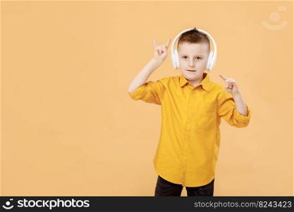 portrait of funny clever school boy with headphones in yellow shirt. Yellow studio background. Education. Looking and smiling at camera.. portrait of funny clever school boy with headphones in yellow shirt. Yellow studio background. Education. Looking and smiling at camera