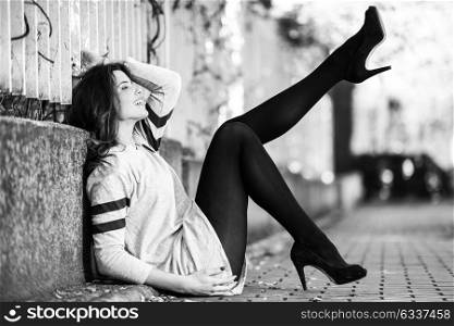 Portrait of funny female model of fashion with high heels sitting on the floor moving her legs
