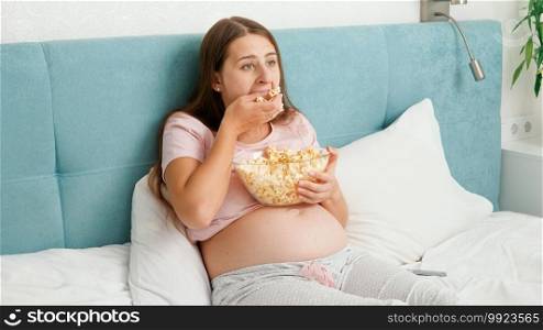 Portrait of funny woman feeling hungry eating popcorn and grabbing it with hand from big bowl. Concept of bulimia and overeating.. Portrait of funny woman feeling hungry eating popcorn and grabbing it with hand from big bowl. Concept of bulimia and overeating