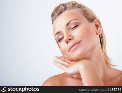 Portrait of gentle calm girl with closed eyes and hand near face over light background, natural skin care, perfect complexion, enjoying day spa