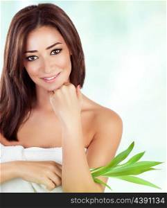 Portrait of gentle female holding fresh green leaves over blur and white background, with pleasure spending day in luxury spa salon