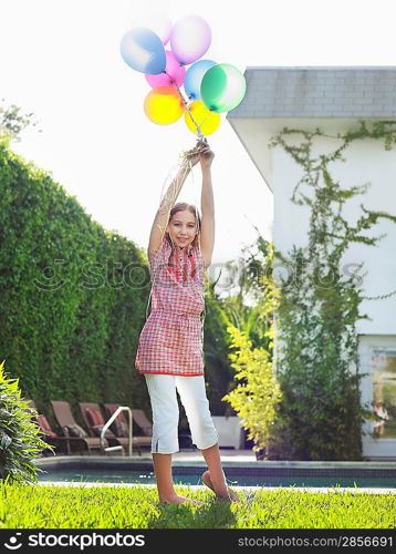 Portrait of girl (10-12) holding bunch of balloons over head