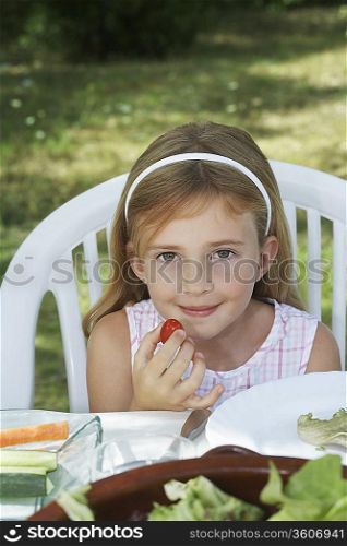 Portrait of girl (5-6) sitting at dinner table in garden