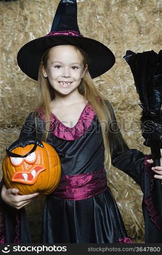 Portrait of girl (7-9) wearing witch costume by hay
