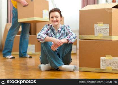 Portrait of girl and boyfriend carrying boxes to new house in background