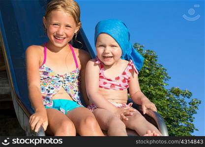 Portrait of girl and female toddler on water slide at Lake Seeoner See, Bavaria, Germany