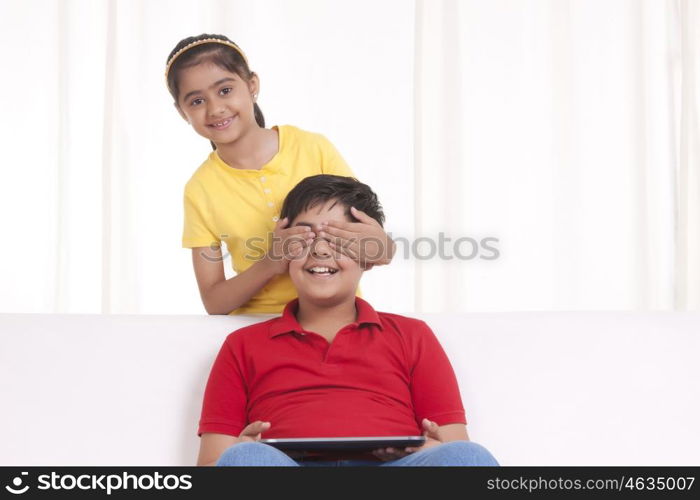 Portrait of girl covering boys eyes