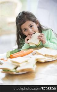 Portrait of girl eating sandwich at home