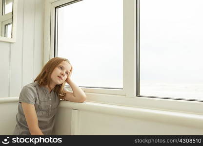 Portrait of girl gazing out of holiday apartment window